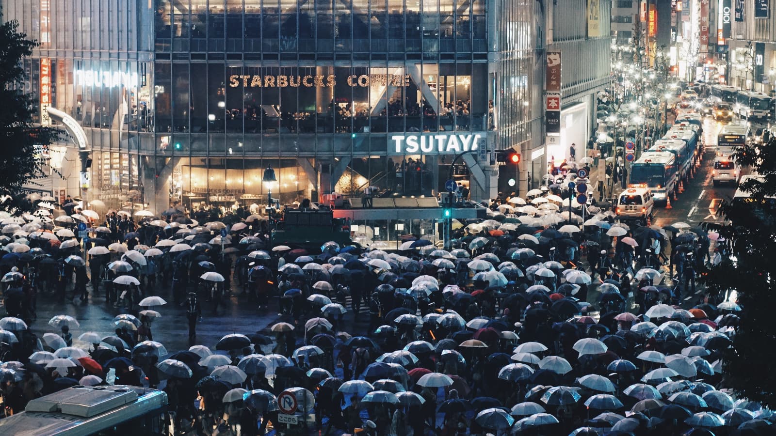 Shibuya Crossing, the busiest intersection in the world, in the rain with iconic transparent Japanese umbrellas.